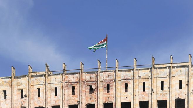 Потрёпанный флаг Абхазии всё ещё развевается на вершине здания