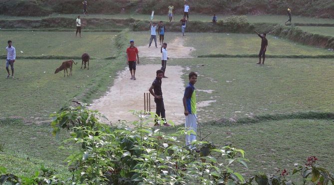 Местная молодежь играет в крикет на пустом участке в чайном саду Лаккатура