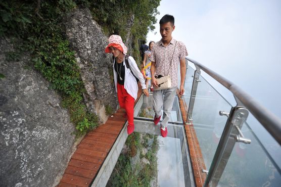 Туристы идут над обрывом по стеклянному мосту длиной 100 м и шириной 1,6 м