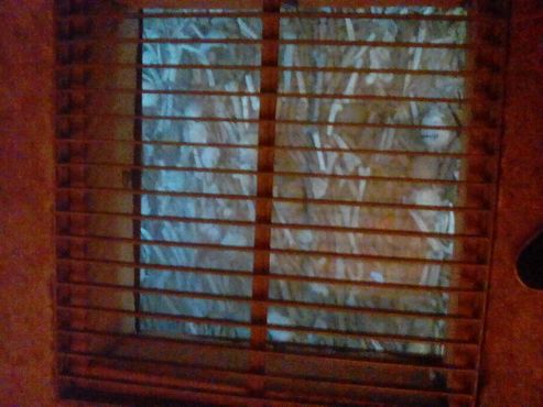 Окно в склеп скрыто грязным листом стекла или плексигласа под решеткой