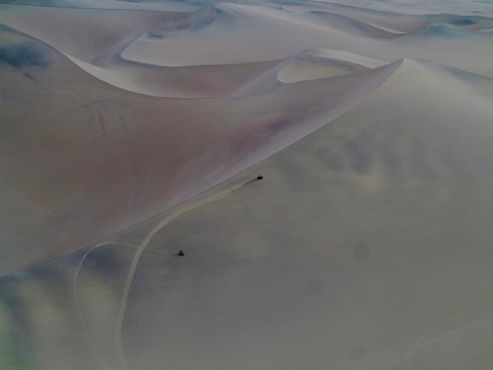 Внедорожники посреди бесконечных изгибов дюн