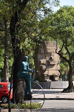Вид на монолит Тлалока и современную скульптуру с другой стороны проспекта Пасео-де-Реформа.