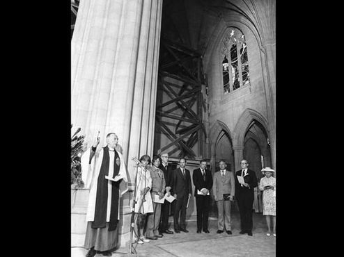 Преподобный Фрэнсис Б. Сэйр-младший освящает Космическое окно, вверху справа, на церемонии 1974 года. На заднем плане стоят астронавты "Аполлона-11" и два директора НАСА
