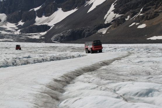 Громадные грузовики перевозят людей через ледник