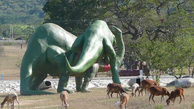 Животные пасутся возле огромных динозавров