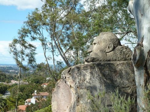 Каменный бюст рядом с заросшей тропинкой в парк на склоне холма