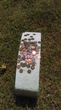 Люди бросают монеты на белое надгробие без надписей