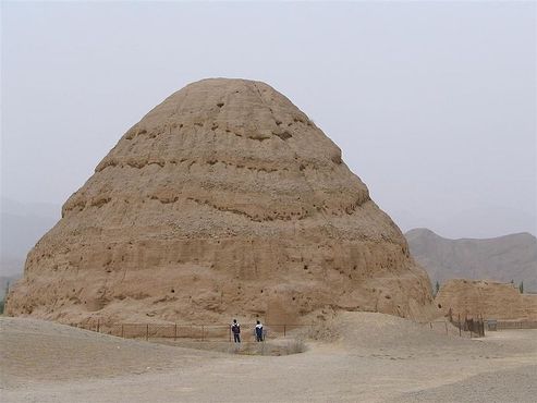 Люди стоят рядом с руинами пирамиды