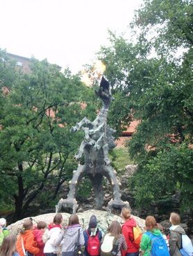 Толпа детей любуется статуей дракона